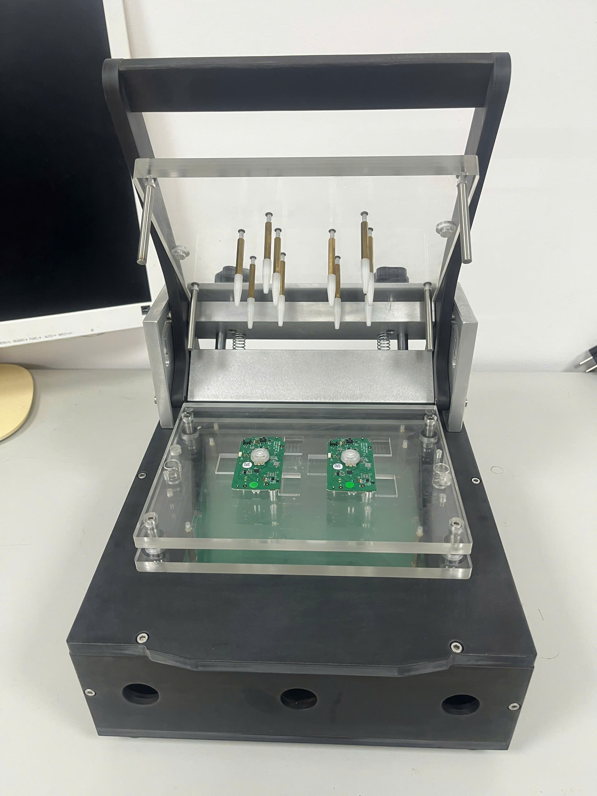 Fixture mở với một bo mạch và vị trí định vị còn trống bên cạnh.